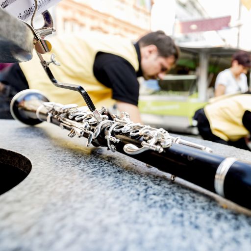 Nahaufnahme Musikfestival Em Bebbi sy Jazz: Klarinette liegt auf einem Brunnen, im Hintergrund sind Musiker und Musikerinnen zu sehen