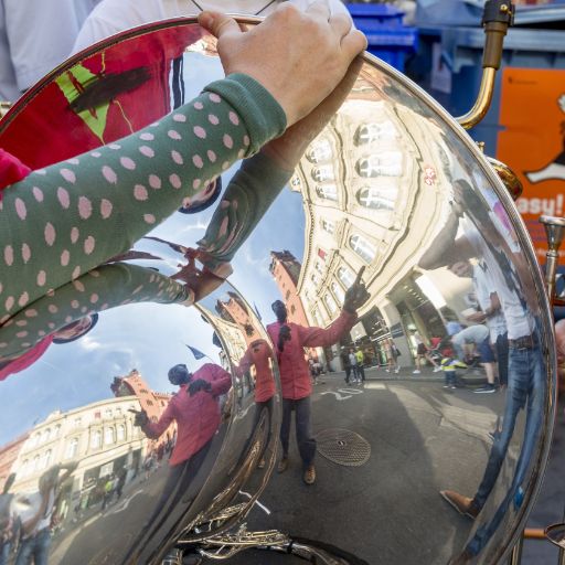 Nahaufnahme Musikfestival Em Bebbi sy Jazz: Kinderarm hält Tuba, darin spiegeln sich Menschen und Häuser